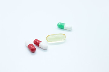 Multi-colored pill capsules are located on a white background
