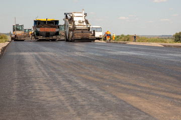 Construction of a new asphalt road or highway. Construction equipment is on svezheokrashennoj paved road.