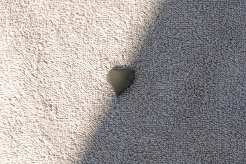 Gray heart-shaped stone lies on a gray Terry towel.