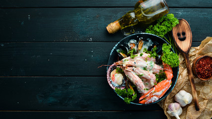 Boiled Seafood in a creamy sauce on a black stone plate. Seafood, prawns, shellfish, lobster. Top view. Free copy space.