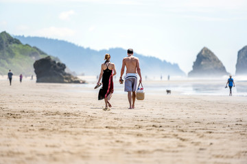 A man and a woman with shoes in their hands and a basket with things walk along the shore of the Northwest Pacific