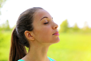 Close up portrait of woman relaxing breathing fresh air deeply in the park.