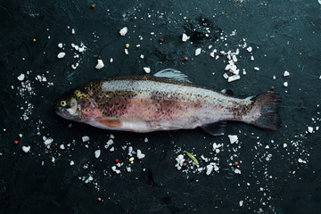 Raw fish trout on a black background. Top view. Free space for your text.
