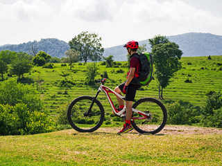 Side view of sports man on mountain bike at rural alpine fields background