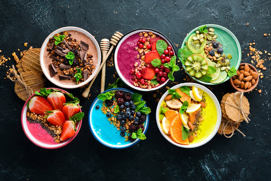 A great set of colored fruit smoothies with yogurt, fresh fruit and berries. A healthy breakfast. Top view. Free space for your text. On a black background.