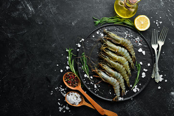Raw black tiger prawns with lemon. Seafood. Top view. On a black background. Free copy space.