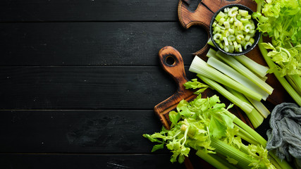 Fresh green celery stalk on a black background. Healthy food. Top view. Free space for your text.