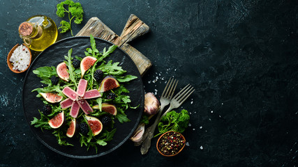 Arugula salad, tuna fillet and figs with blackberry berries. Menu. Free copy space. Top view.