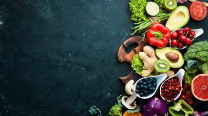 Fresh vegetables and fruits on a black background. Vitamins and minerals. Top view. Free space for...