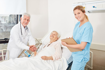 Kranke Seniorin im Bett als zufriedene Patientin