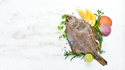 Raw flounder fish with spices. Seafood on a white wooden background. Top view. Free copy space.