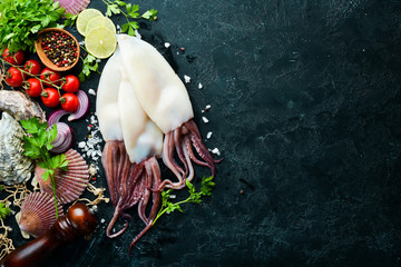 Raw squid with spices. Seafood on a black stone background. Top view. Free copy space.