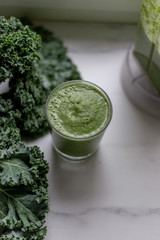 Green smoothies with kale, banana and apple on marble background with copy space