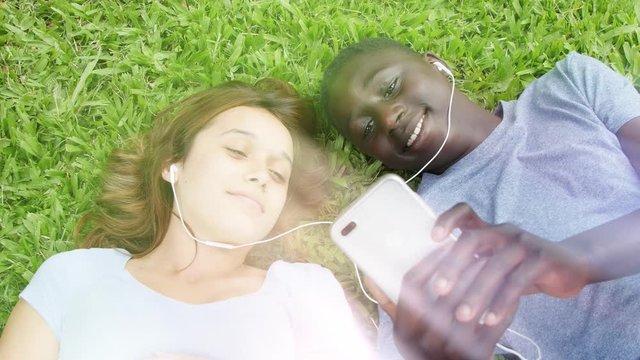 Mixed race young couple outdoor hearing music