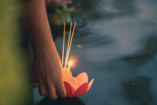 Paper lotus flower with candle floating on a river at night in Loy krathong festival, traditional Siamese new year festival celebrated in Thailand.