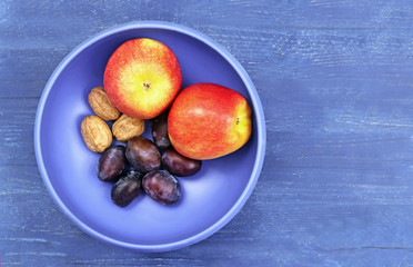 blue fruit bowl with apples, walnuts and plums