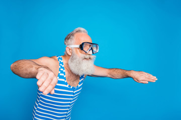 Profile side photo of concentrated pensioner swimming in glasses wearing striped bathing suit isolated over blue background
