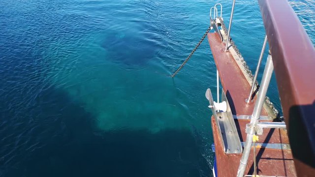 A boat drops anchor as the chain unravels into the sea