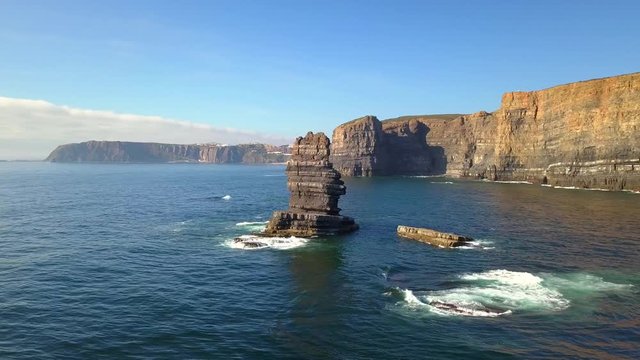Aerial, drone shot, around a large rock, on the Atlantic sea, near cliffs, at Arrifana Beach, on a sunny day, in Parque Natural do Sudoeste Alentejano e Costa Vicentina, in Portugal