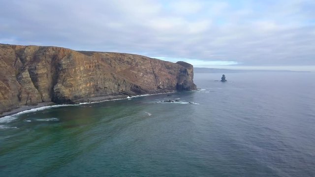 Aerial, reverse, drone shot, panning towards the Arrifana Beach, cliffs and buildings on the Atlantic coast, on a sunny day, in Parque Natural do Sudoeste Alentejano e Costa Vicentina, in Portugal