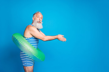 Profile side photo of impressed old man jumping with rubber round circle wearing striped swim wear...