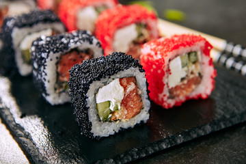 Macro photo of maki sushi roll with rice, cream cheese, salmon, eel, cucumber, flying fish caviar....
