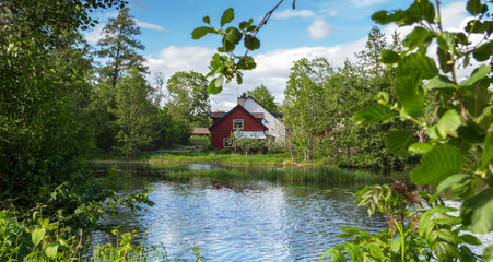 Red cabin and estate right by a small lake and nature in Scandinavia. Nice colors and lights. - 285001490