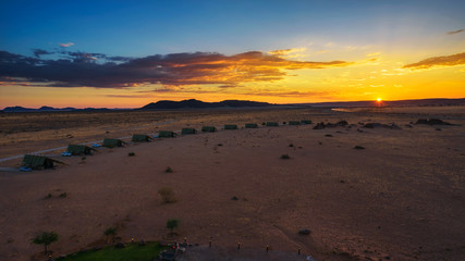 Sunset above small chalets of a desert lodge near Sossusvlei in Namibia