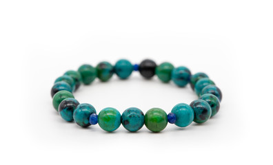 Bracelet made of blue and green chrysocolla stone on a white background, close-up, selective focus.