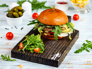 Burger with arugula and pickles. Restaurant serving.