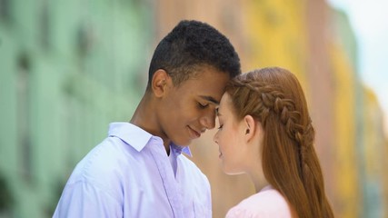 Multiethnic teen couple touching foreheads looking into eyes with love, romance - Powered by Adobe