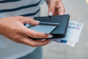 cropped view of woman holding euro banknotes and credit card with wallet