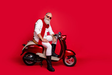 Obraz na płótnie Canvas Gangster grandfather santa man sitting on retro moped wear jumper and trousers isolated red background