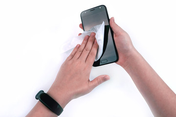 Girl's hand with a white napkin wipes the screen of the smartphone black, on a white background. Fitness tracker on hand  