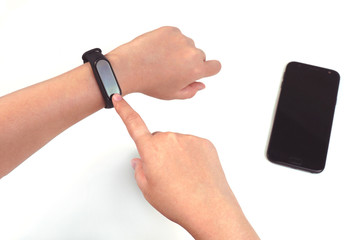                The girl's hand activates the fitness tracker with her finger on a white background.  Next to the smartphone.