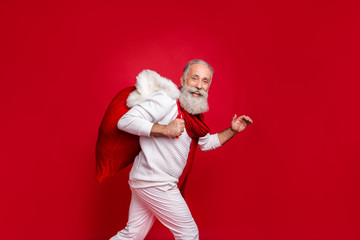 Hipster senior man modern santa at party bring presents wearing fashion knitted clothes isolated red background