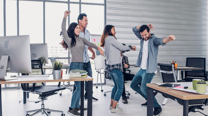 group of creative designer dancing in office with relax feeling and glad about good success news of...
