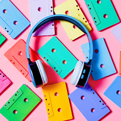 Painted audio cassettes and blue headphones on bright background, copy space, top view. Retro music background
