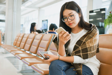 Young asian woman using smartphone while she waiting airplane in the airport.