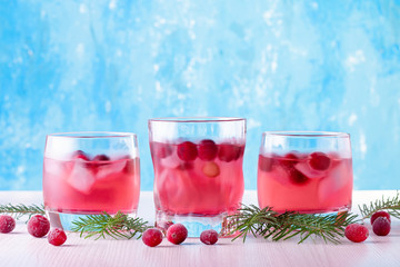 Winter non alcoholic cocktail with cranberry and ice on bright blue background, closeup