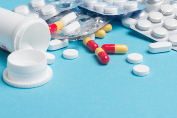 Mix of medicines, pills, drugs on a blue background.