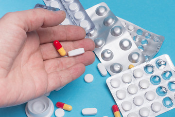 medical tablets in the hand of a person on the background of medicines