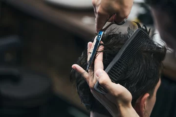 Foto auf Acrylglas Antireflex Barbershop. Close-up of man haircut, master does the hair styling in barber shop. Close-up, master Barber does the hairstyle and styling with scissors. Concept Barbershop. © Graphicroyalty