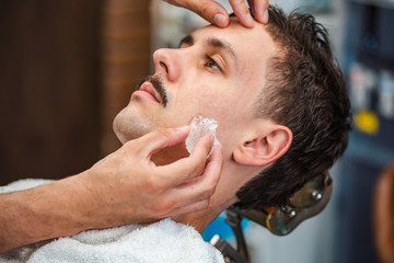 Barber closing mans pores with alum stone. Traditional ritual of after shaving the beard with alum stone. Client getting his face rubbed with alum stone after shaving in barber shop