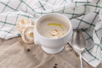 champignon cream soup in white bowl with napkin on grey tablecloth