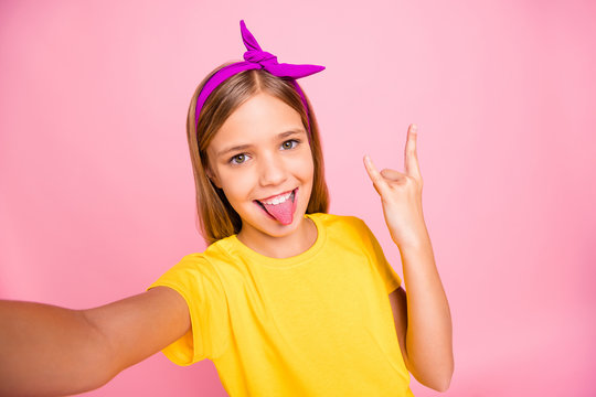 Self-portrait of her she nice attractive lovely crazy cheerful cheery pre-teen girl wearing yellow t-shirt showing horn symbol heavy metal rock roll having fun isolated over pink pastel background
