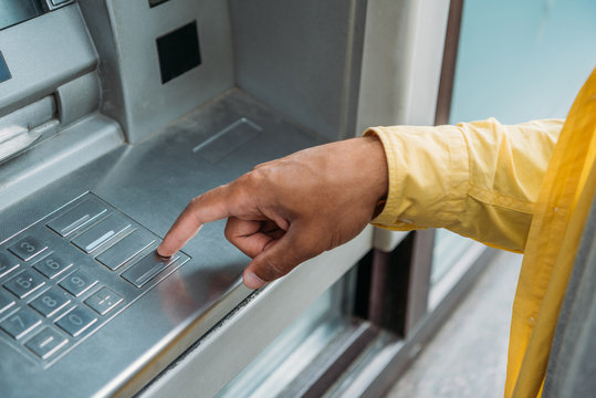 cropped view of bi-racial man pressing button on atm keyboard