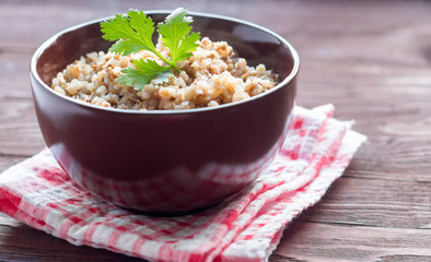 a bowl of cooked buckwheat on wooden background