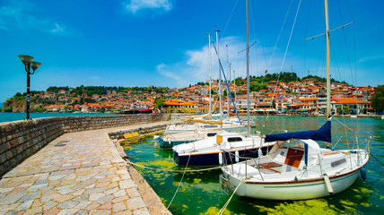 North macedonia. Ohrid. Different sail boats in dock on lake with buildings on hill - obrazy, fototapety, plakaty