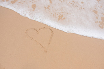 Draw a heart on the sand at the beach is a tourist attraction. a symbol of love On valentines day. background and texture.